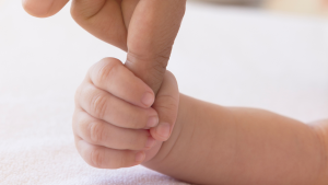 Mano de un bebé cogiendo con confianza interior la mano de su padre