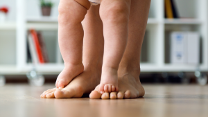 Los pies de un bebé de pie sobre la firmeza interior de los pies de su padre